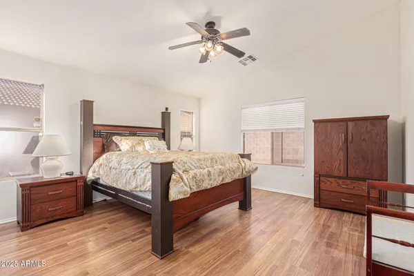 a bedroom with a bed and a dresser with wooden floor