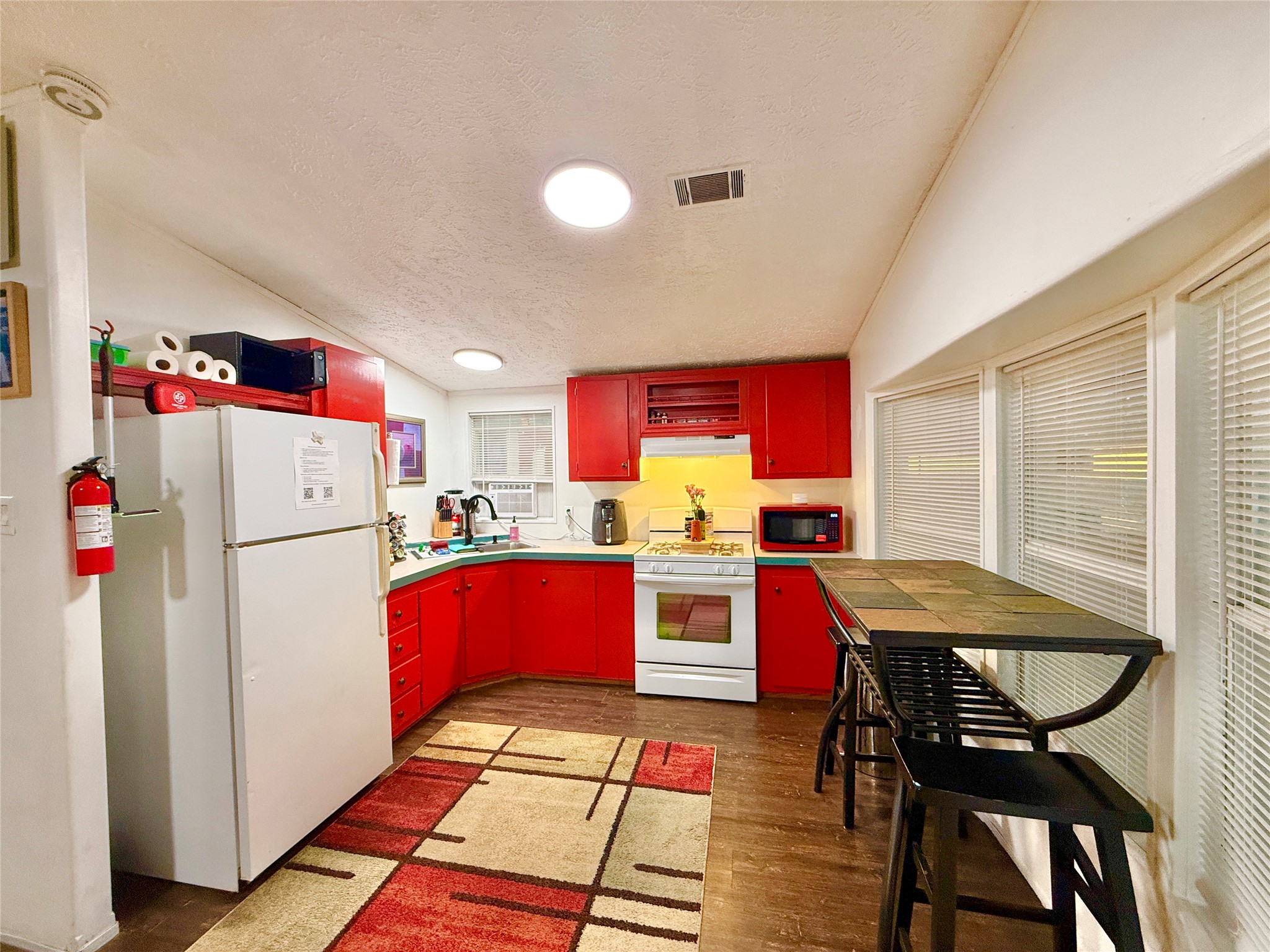2015 Holly Street Austin, TX 78702 - Photo 7 of 24 A vibrant kitchen features a breakfast bar, ample cabinetry, and practical appliances, all beneath high ceilings.