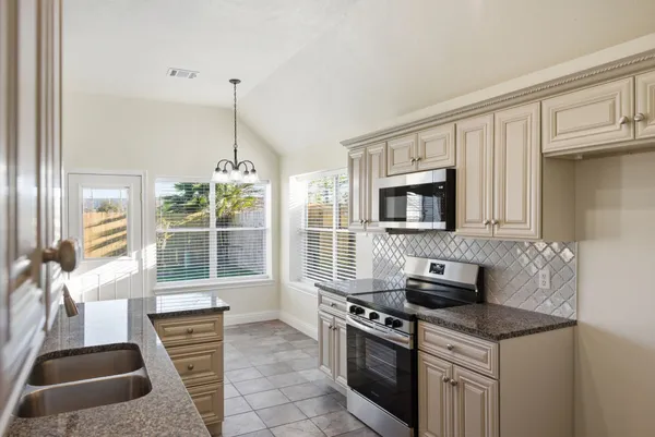 a kitchen with stainless steel appliances granite countertop a stove a sink and a microwave