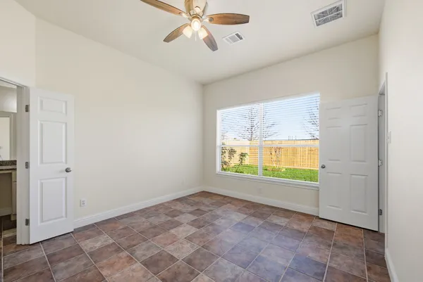 an empty room with windows and a ceiling fan