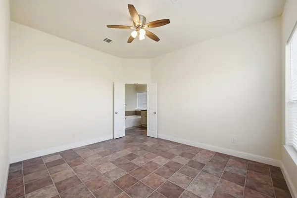 an empty room with a ceiling fan and carpet