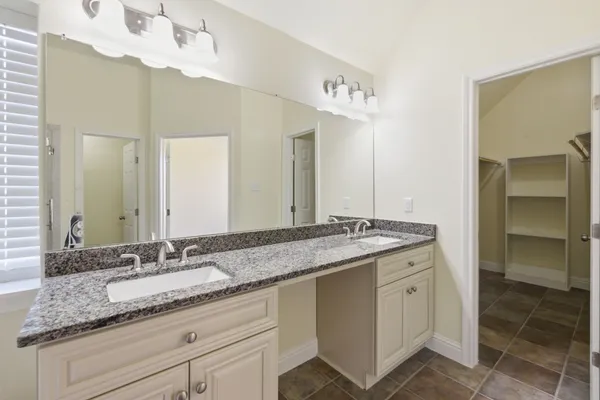 a bathroom with a granite countertop double vanity sink and a mirror