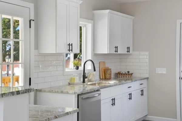 a kitchen with stainless steel appliances granite countertop a sink and a white cabinets