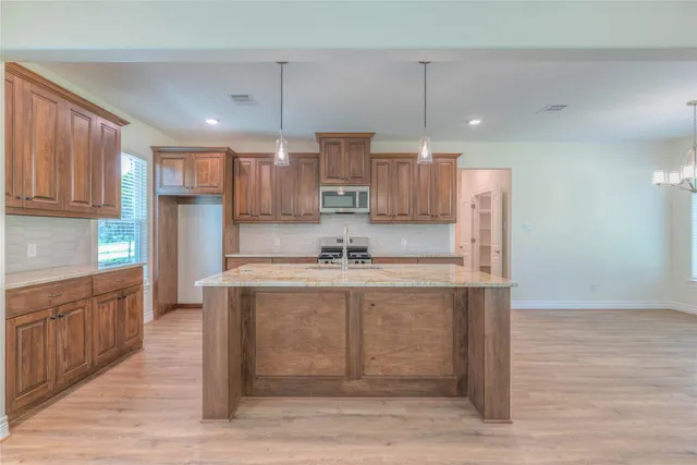 a large kitchen with stainless steel appliances granite countertop a sink a stove and a wooden floors