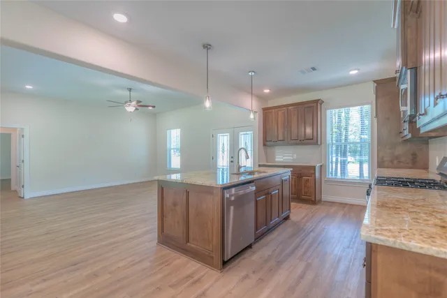 a kitchen with granite countertop wooden floors wooden cabinets a sink and appliances