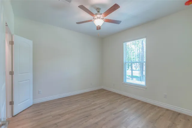 a view of an empty room with a window and wooden floor