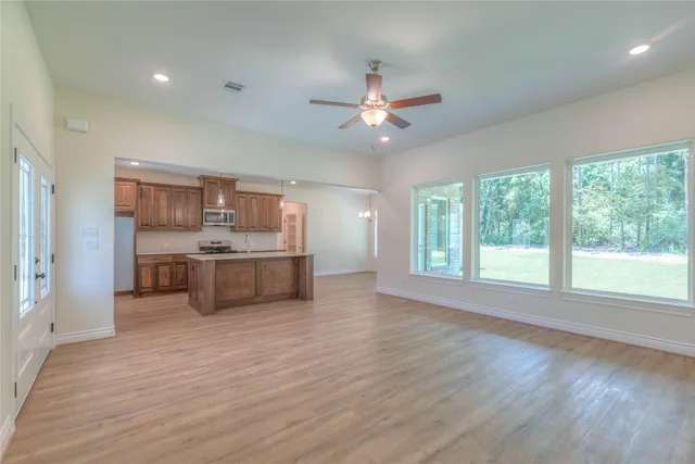 a view of an empty room with a window and wooden floor