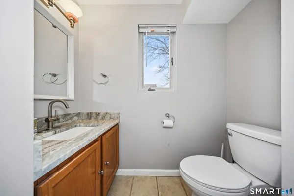 a bathroom with a granite countertop toilet sink and mirror