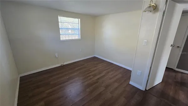 an empty room with wooden floor and window