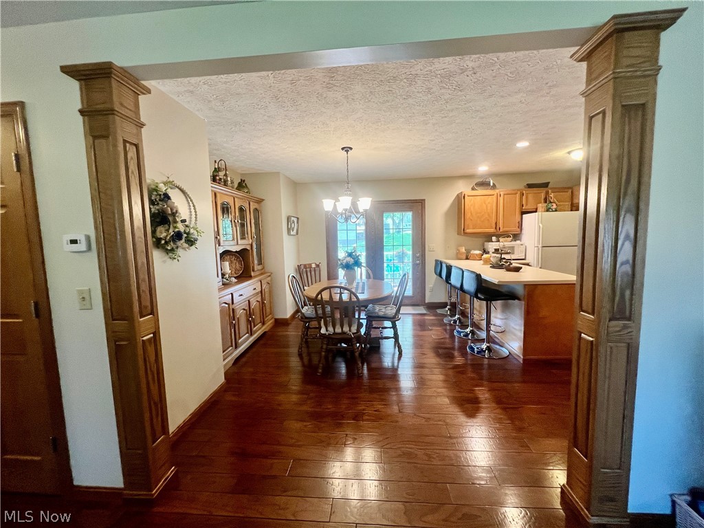 53360 High Ridge Road Bridgeport, OH 43912 - Photo 7 of 41 Dining room featuring a textured ceiling, an inviting chandelier, hardwood / wood-style floors, and ornate columns