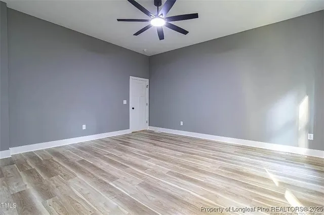 a view of an empty room and chandelier fan