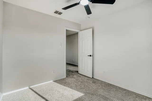 an empty room with a ceiling fan and carpet