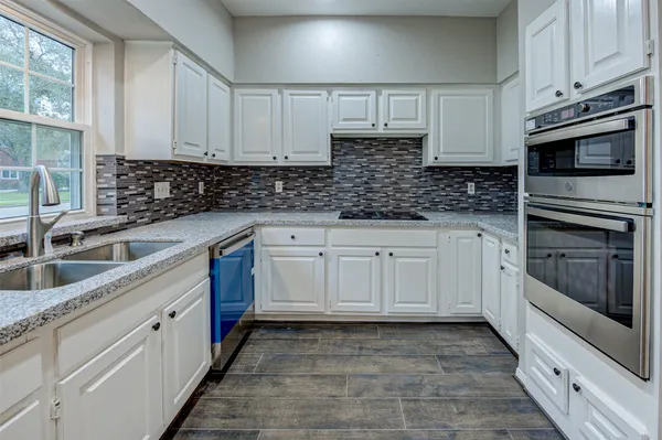 a kitchen with granite countertop white cabinets and stainless steel appliances