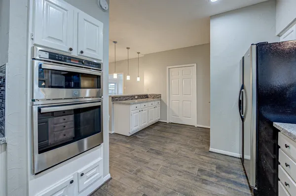 a kitchen with cabinets stainless steel appliances and wooden floor