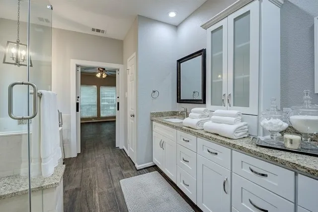a bathroom with a granite countertop sink a toilet a mirror and shower