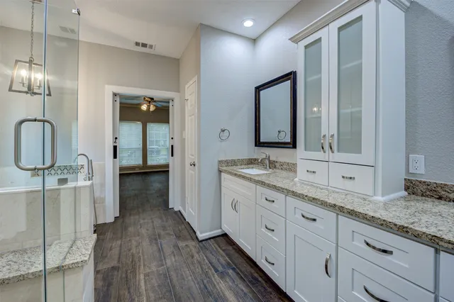 a bathroom with a granite countertop sink a toilet and a shower