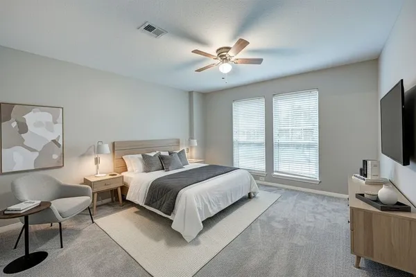 a spacious bedroom with a bed and a flat screen tv