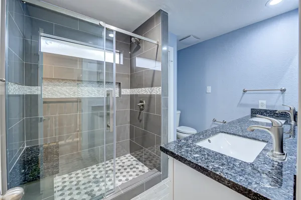 a bathroom with a granite countertop sink a toilet and shower