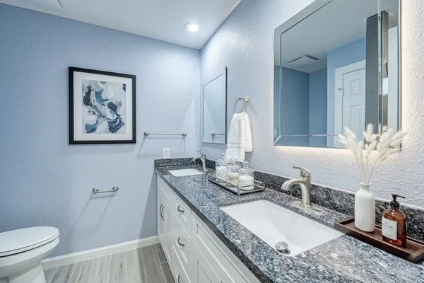 a bathroom with a granite countertop toilet a sink and a mirror