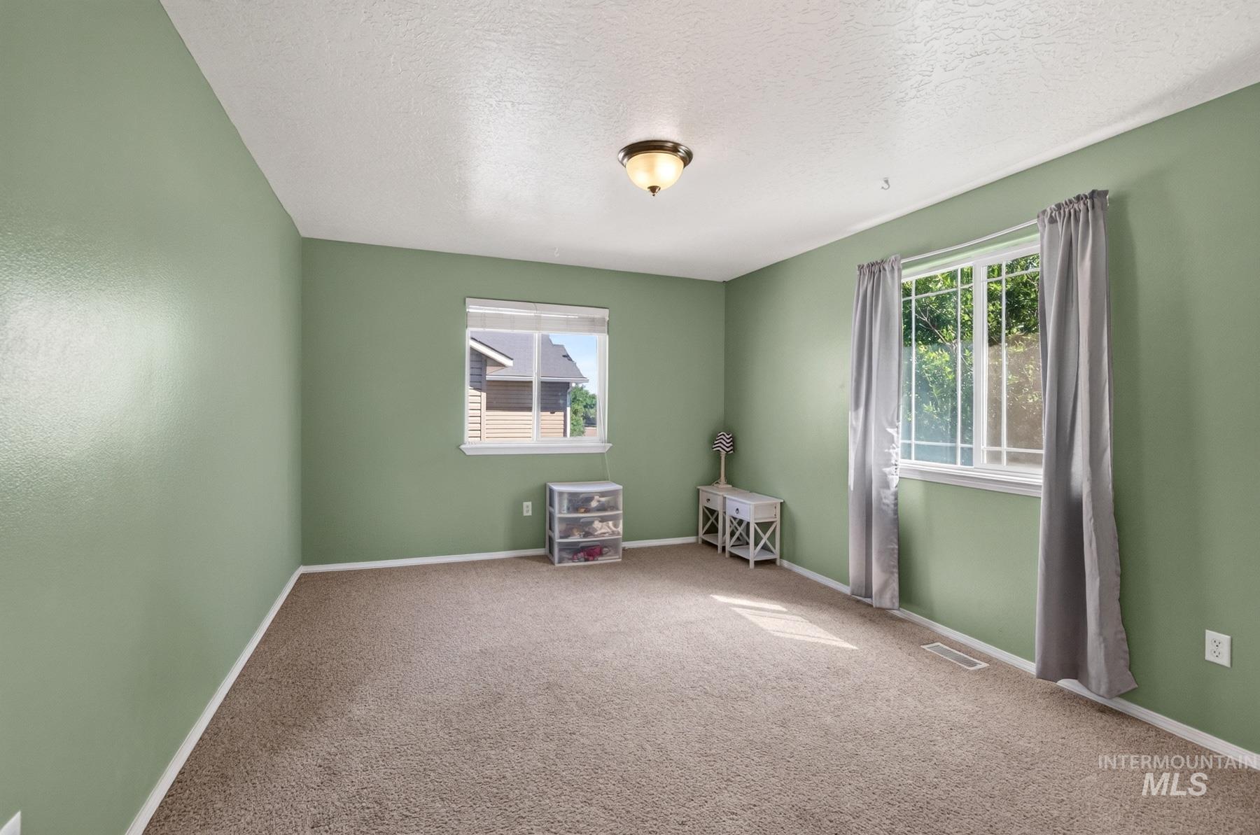 5020 Northrup Way Caldwell, ID 83607 - Photo 23 of 36 Carpeted room featuring light green walls, white trim, and a textured white ceiling