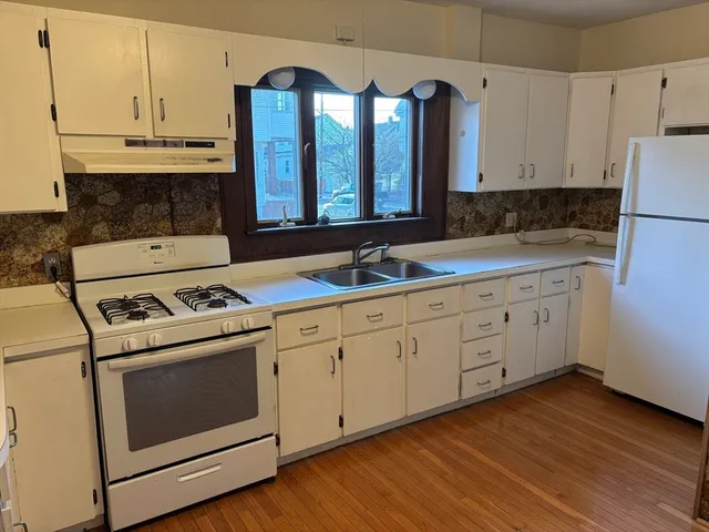 a kitchen with cabinets stainless steel appliances a sink and wooden floor