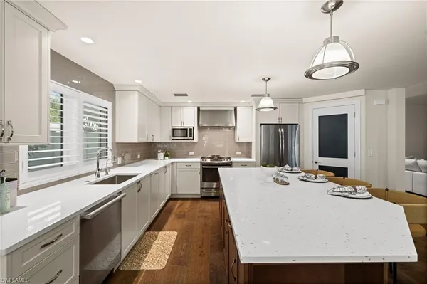 a large white kitchen with kitchen island a stove a sink a center island and furniture
