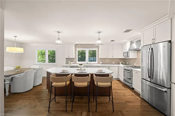 a kitchen with stainless steel appliances a dining table and chairs