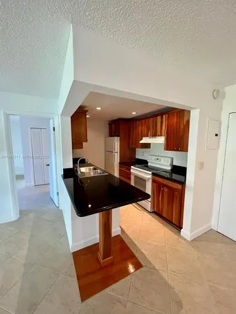a living room with stainless steel appliances furniture a rug and a kitchen view