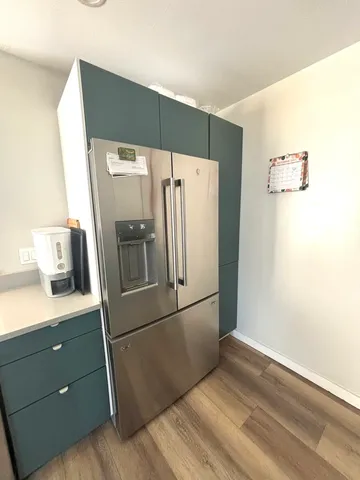 a kitchen with metallic refrigerator and wooden floor