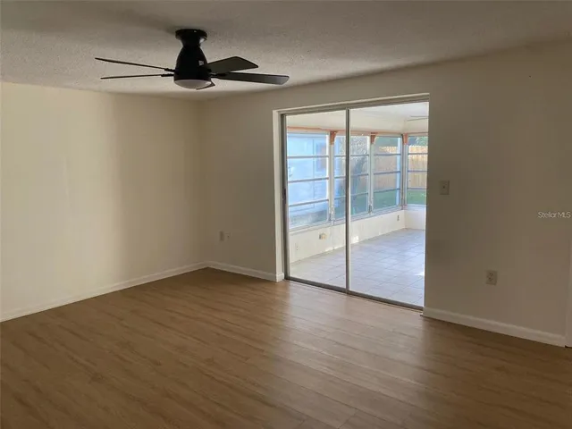 a view of an empty room with wooden floor and a window