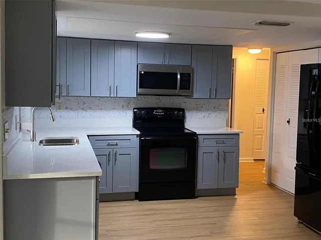 a kitchen with stainless steel appliances granite countertop a stove a sink and a microwave