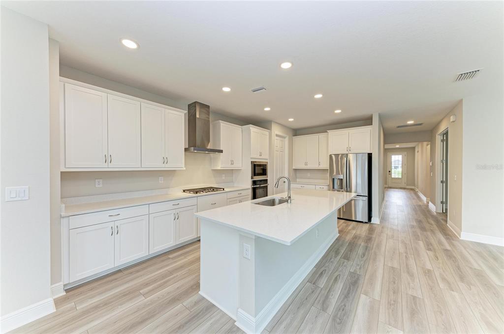 17915 Cropside Trail Lakewood Ranch, FL 34211 - Photo 13 of 33 a large white kitchen with wooden floor and a sink