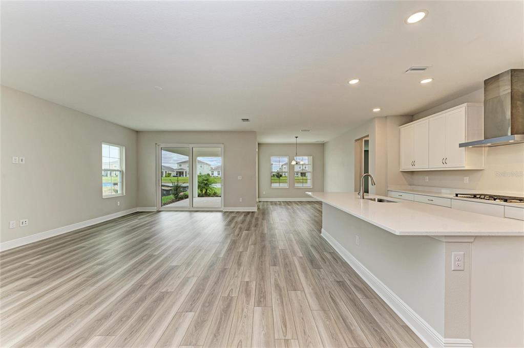 17915 Cropside Trail Lakewood Ranch, FL 34211 - Photo 17 of 33 a large kitchen with stainless steel appliances a large window a oven and white cabinets with wooden floor