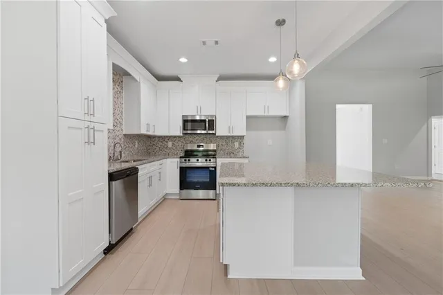 a kitchen with stainless steel appliances granite countertop a stove a sink and a granite counter tops with white cabinets
