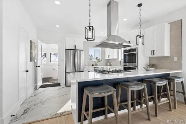 a kitchen with stainless steel appliances a stove a sink island and a refrigerator with wooden floor