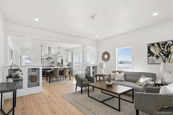 a living room with furniture kitchen view and a wooden floor