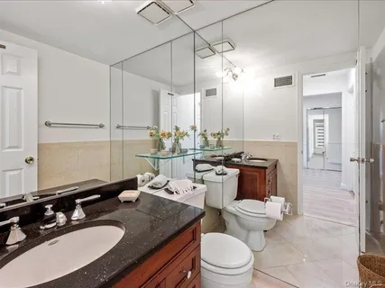 a bathroom with a granite countertop sink a toilet and a mirror
