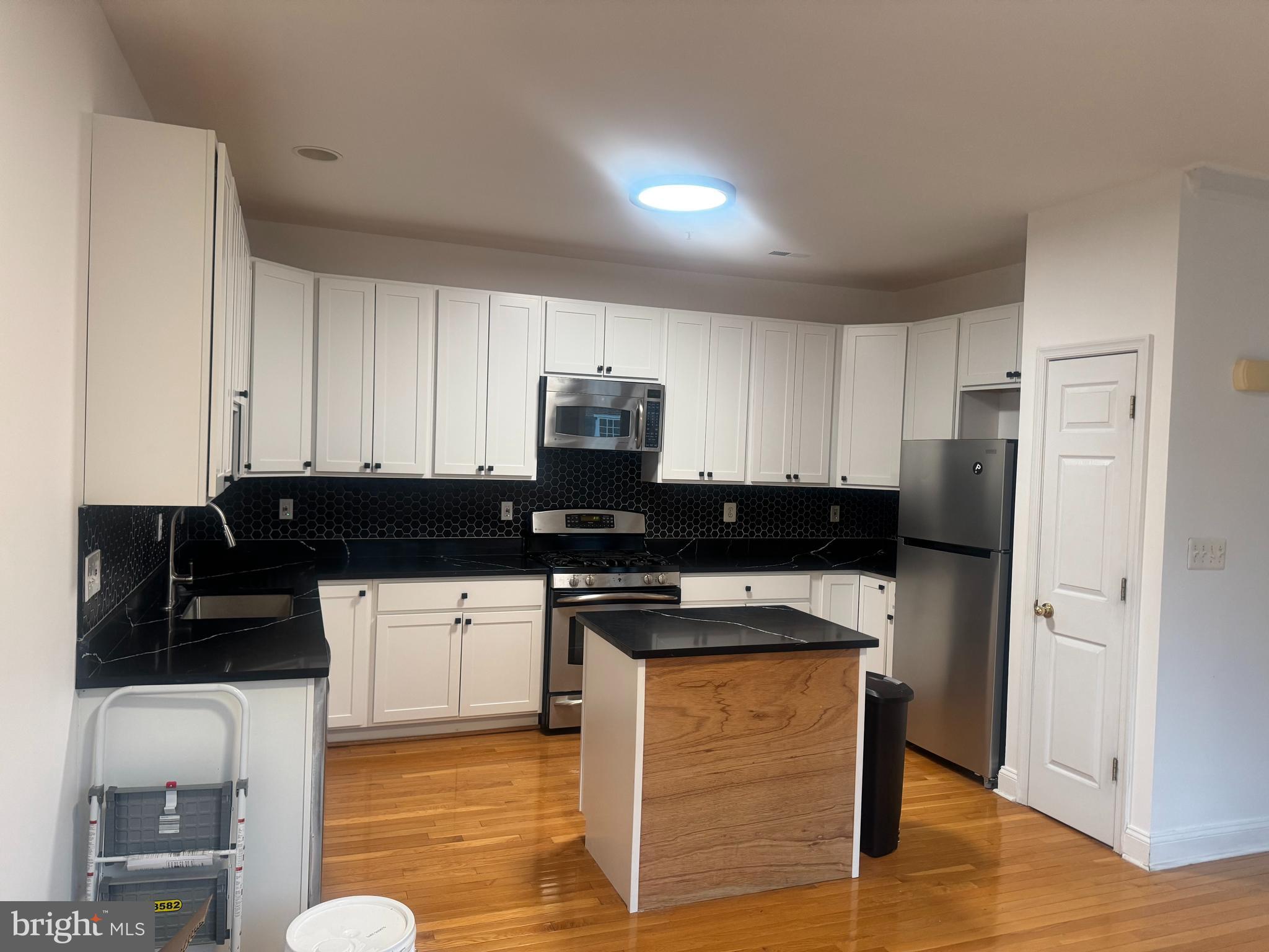 127 Albemarle Street, Unit 36 Baltimore, MD 21202 - Photo 8 of 25 a kitchen with stainless steel appliances kitchen island granite countertop a stove a sink a refrigerator and white cabinets