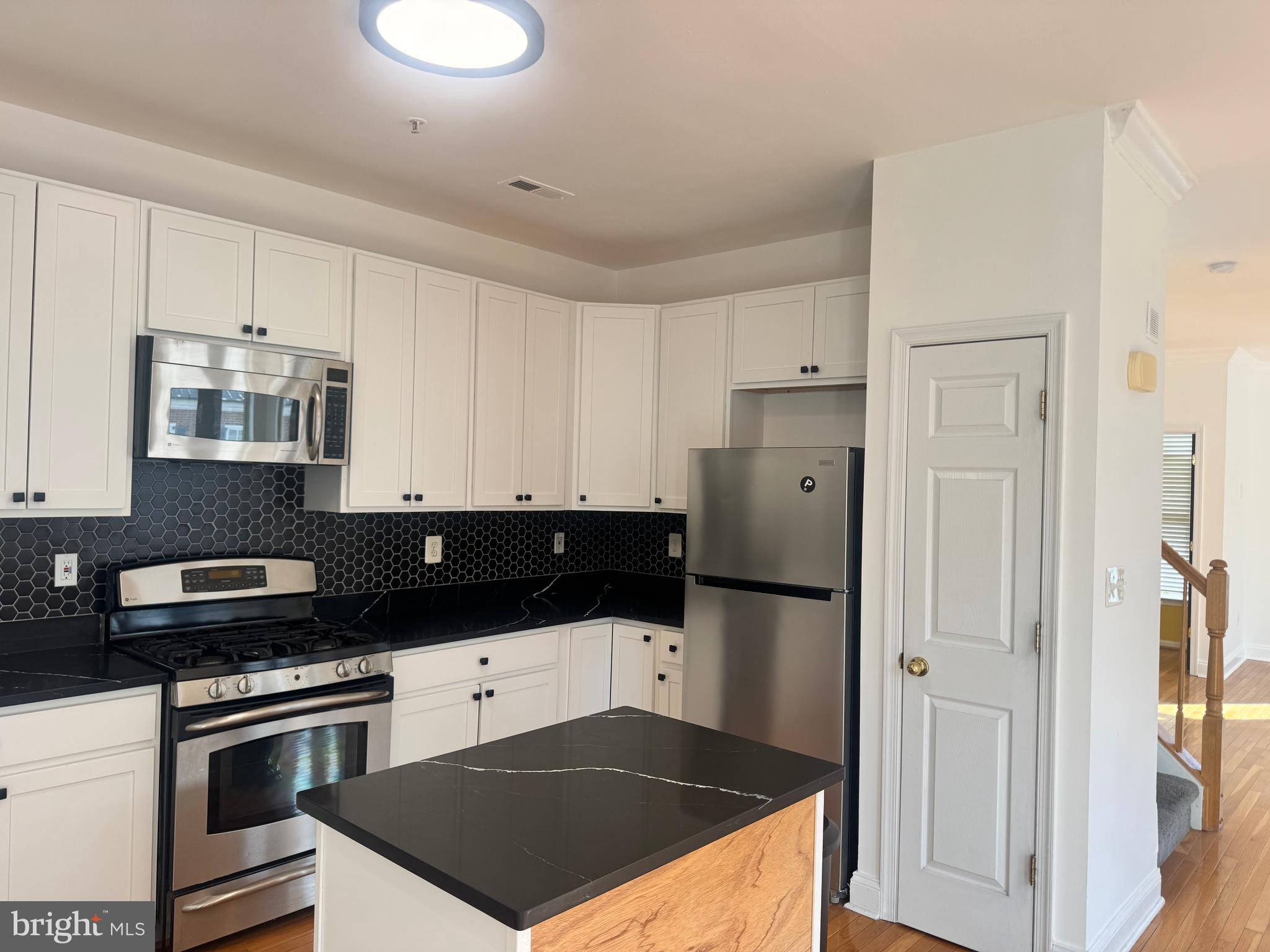 127 Albemarle Street, Unit 36 Baltimore, MD 21202 - Photo 9 of 25 a kitchen with granite countertop a refrigerator and a stove top oven