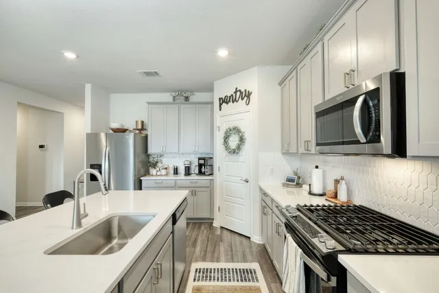 a kitchen with stainless steel appliances granite countertop a stove a sink a refrigerator with a dining table and chairs