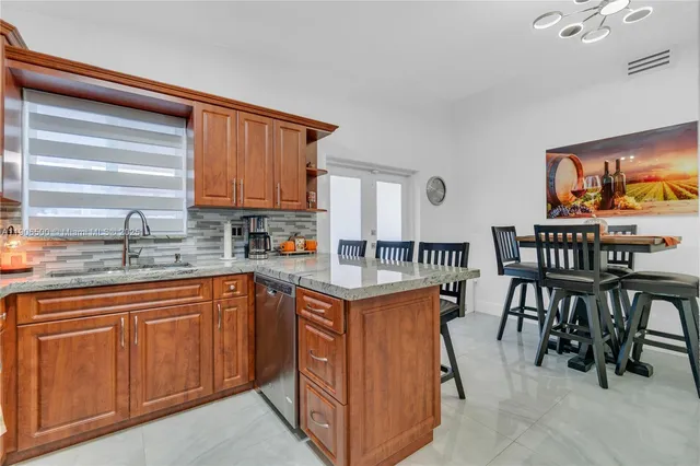 a kitchen with stainless steel appliances granite countertop wooden cabinets a dining table and chairs