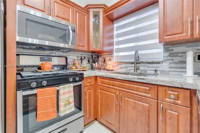 a kitchen with granite countertop stainless steel appliances a sink stove and cabinets