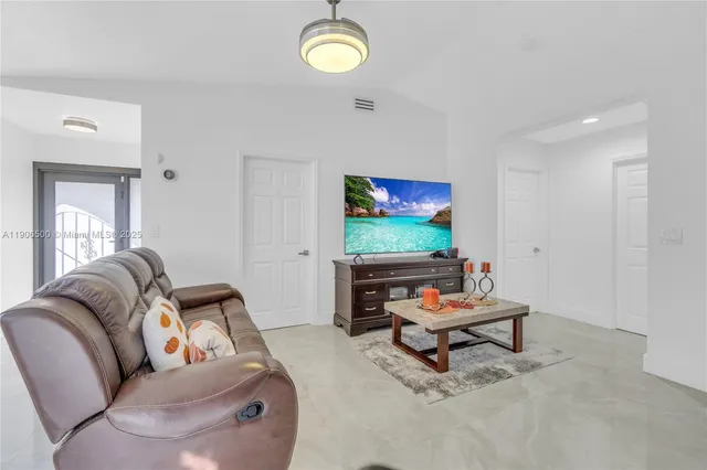 a living room with furniture a flat screen tv and a window