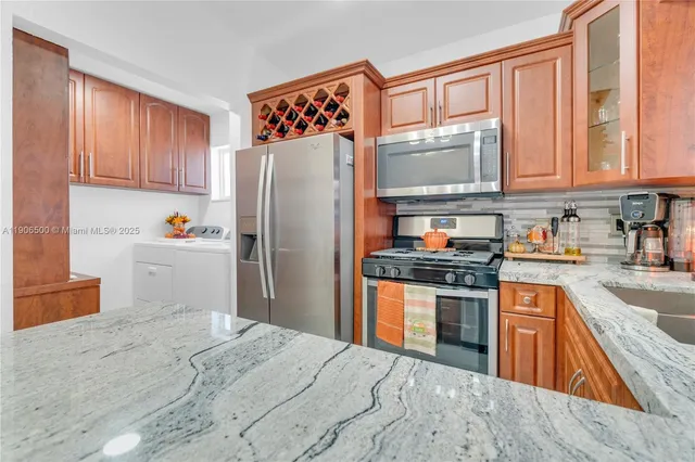 a kitchen with stainless steel appliances granite countertop a refrigerator sink stove microwave and cabinets
