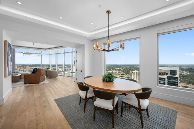 a view of a dining room and livingroom with furniture wooden floor a chandelier