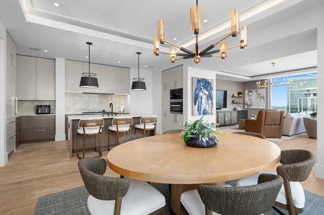 a kitchen with stainless steel appliances kitchen island granite countertop a dining table chairs and a refrigerator