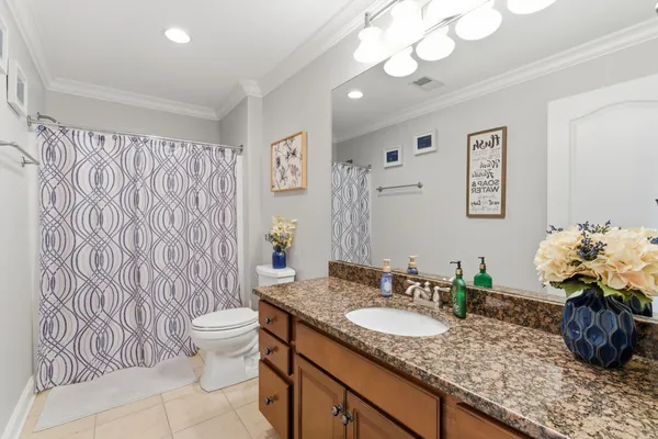 a bathroom with a granite countertop toilet a sink a mirror and shower curtain