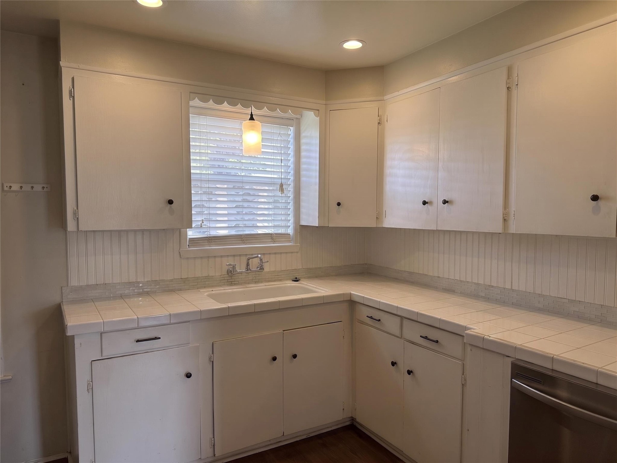 2313 Avenue L Rosenberg, TX 77471 - Photo 11 of 31 Kitchen featuring abundant cabinetry, tile countertops, recessed lighting, and a window overlooking the sink.