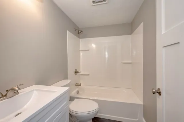 a bathroom with a granite countertop bathtub shower sink vanity mirror and toilet
