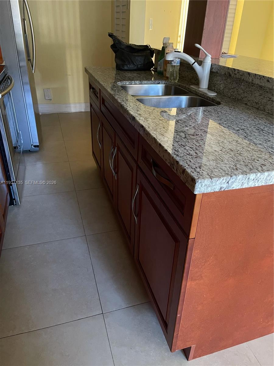 9408 Southwest 140th Court, Unit 9408 Miami, FL 33186 - Photo 3 of 8 a kitchen with granite countertop a sink a stove and a microwave oven in a cabinets